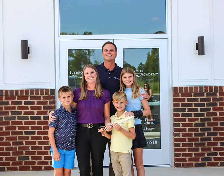 Family of five smiling at the camera in front of their Ivybrook location